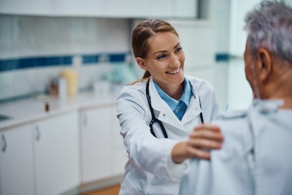 Happy doctor talking to her mature patient during medical exam at the clinic.